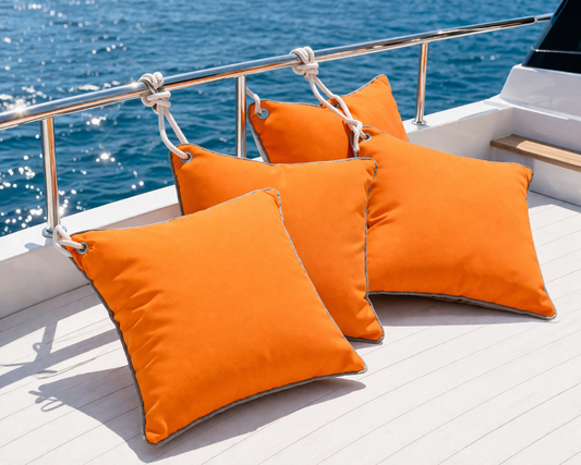 Orangene Yachtkissen / Bootskissen mit grauer Keder Umrandung und rostfreier Öse um mit einem Seil das Kissen am Boot zu befestigen. - von chillisy hergestellt in Deutschland - dargestellt auf einem Boot an der Reling auf dem Wasser.