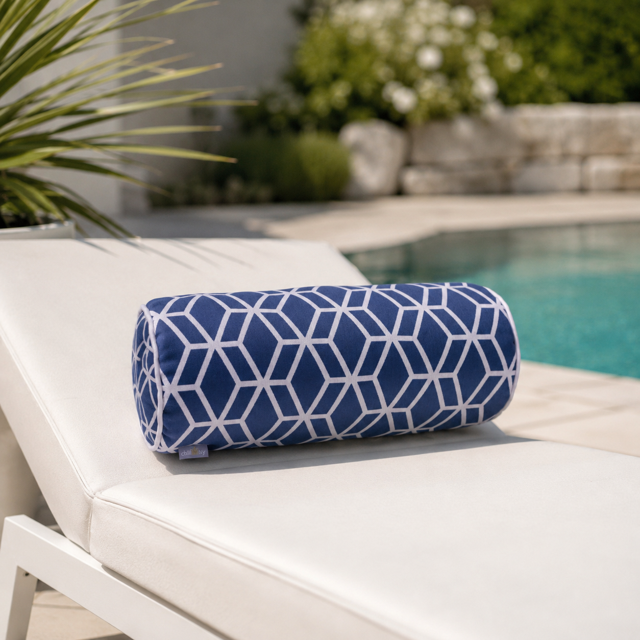 Blaue Designer-Nackenrolle Crystal Gold von chillisy® mit weißem geometrischem Muster auf einer eleganten Sonnenliege am Pool.