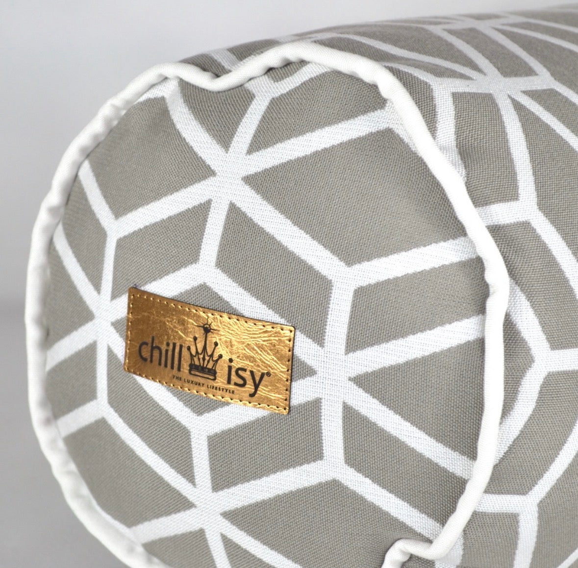 Detailansicht der Designer-Nackenrolle Crystal Gold von chillisy® in Hellgrau mit weißem geometrischem Muster, weißem Keder und Goldlabel.