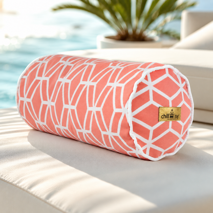 Korallenfarbene Designer-Nackenrolle Crystal Gold von chillisy® mit weißem geometrischem Muster, weißem Keder und Goldlabel auf einer luxuriösen Pool-Lounge.