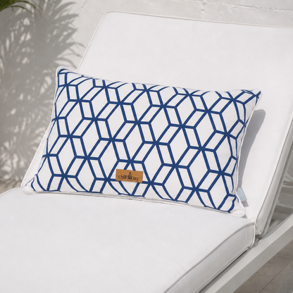 Luxuriöses Outdoor-Dekokissen mit weißem Grundstoff und marineblauem geometrischem Muster auf einer eleganten weißen Gartenlounge mit Meerblick. Das Kissen besitzt einen weißen Keder und das goldene chillisy®-Label und ist handgefertigt in Deutschland – ideal für Terrasse, Garten und Lounge.