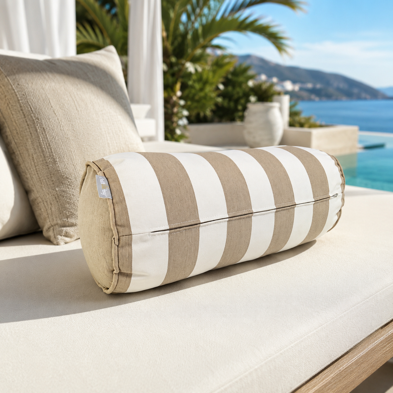 Detailaufnahme einer runden chillisy® Outdoor-Nackenrolle in Beige und Weiß mit breiten Blockstreifen, weißem Keder und dezentem Goldlabel. Hochwertiges Designerkissen für Garten, Terrasse, Lounge oder Poolbereich – Made in Germany.