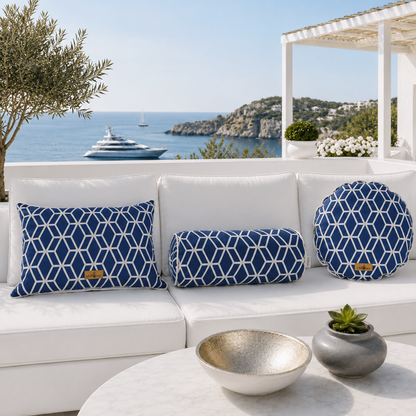 Luxuriöses Outdoor-Designerkissen-Set von chillisy® auf einem weißen Gartensofa mit rechteckigem Kissen, Nackenrolle und rundem Kissen im blau-weißen geometrischen Muster vor exklusiver Meer- und Yachtkulisse.