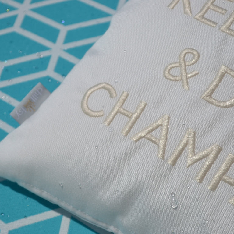 Details des Dekokissen KEEP CALM & DRINK CHAMPAGNE in weiß wollweiss mit Krone bestickt.
