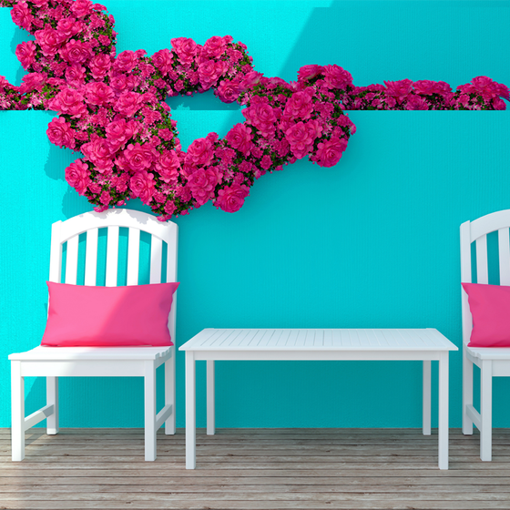 Pinkes Gartenkissen aus Sunbrella Textil auf weißem Stuhl vor türkiser Wand, hergestellt in Deutschland von chillisy. 
