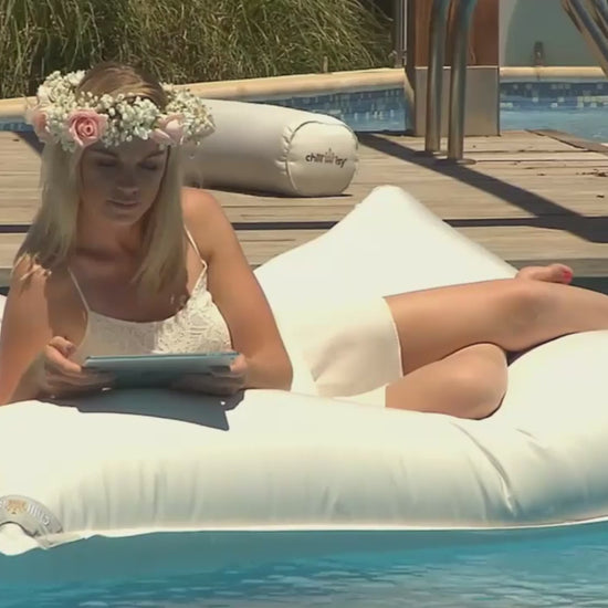 Video mit weißem Poolkissen und Frau im Kleid darauf auf Pool in Mallorca schwimmend.