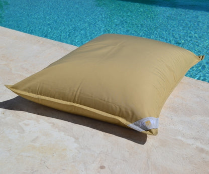 Premium Poolkissen von chillisy in der Farbe Butter Karamell Gold am Poolrand liegend.