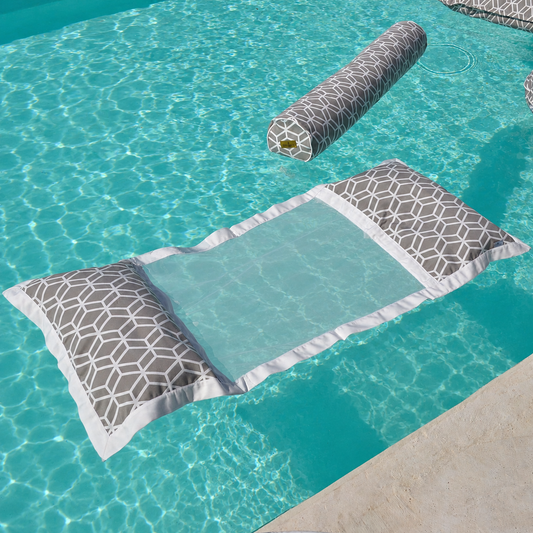 Graue Wasserhängematte mit geometrischem Muster und passender Nackenrolle, schwebend auf kristallklarem türkisfarbenem Poolwasser – hochwertige Detailaufnahme für luxuriöse Entspannung im Pool.